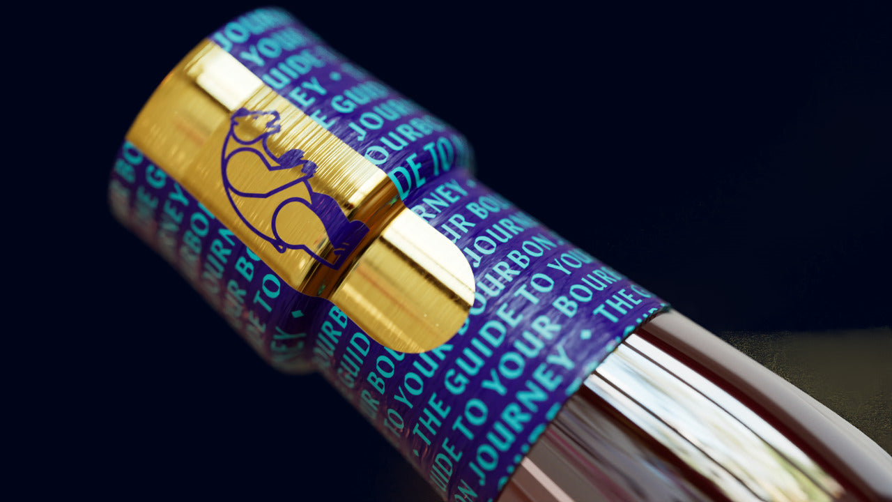 The gold cap and the teal neck wrap printed with The guide to your bourbon journey