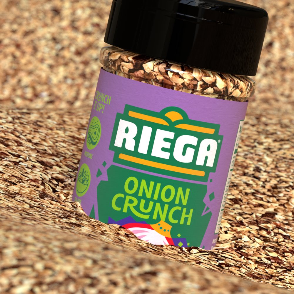 An Onion Crunch jar lies tilted in a bed of its own toasted seasoning flakes.