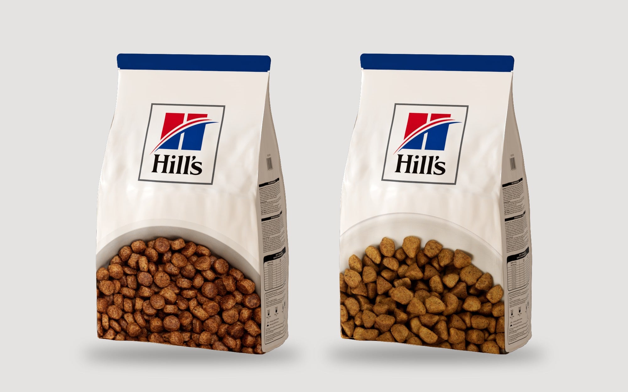 The Dog and Cat master bags side by side on light grey: white bags with a blue top band, the Hill's mark, and a window showing brown dog kibble and smaller golden cat kibble