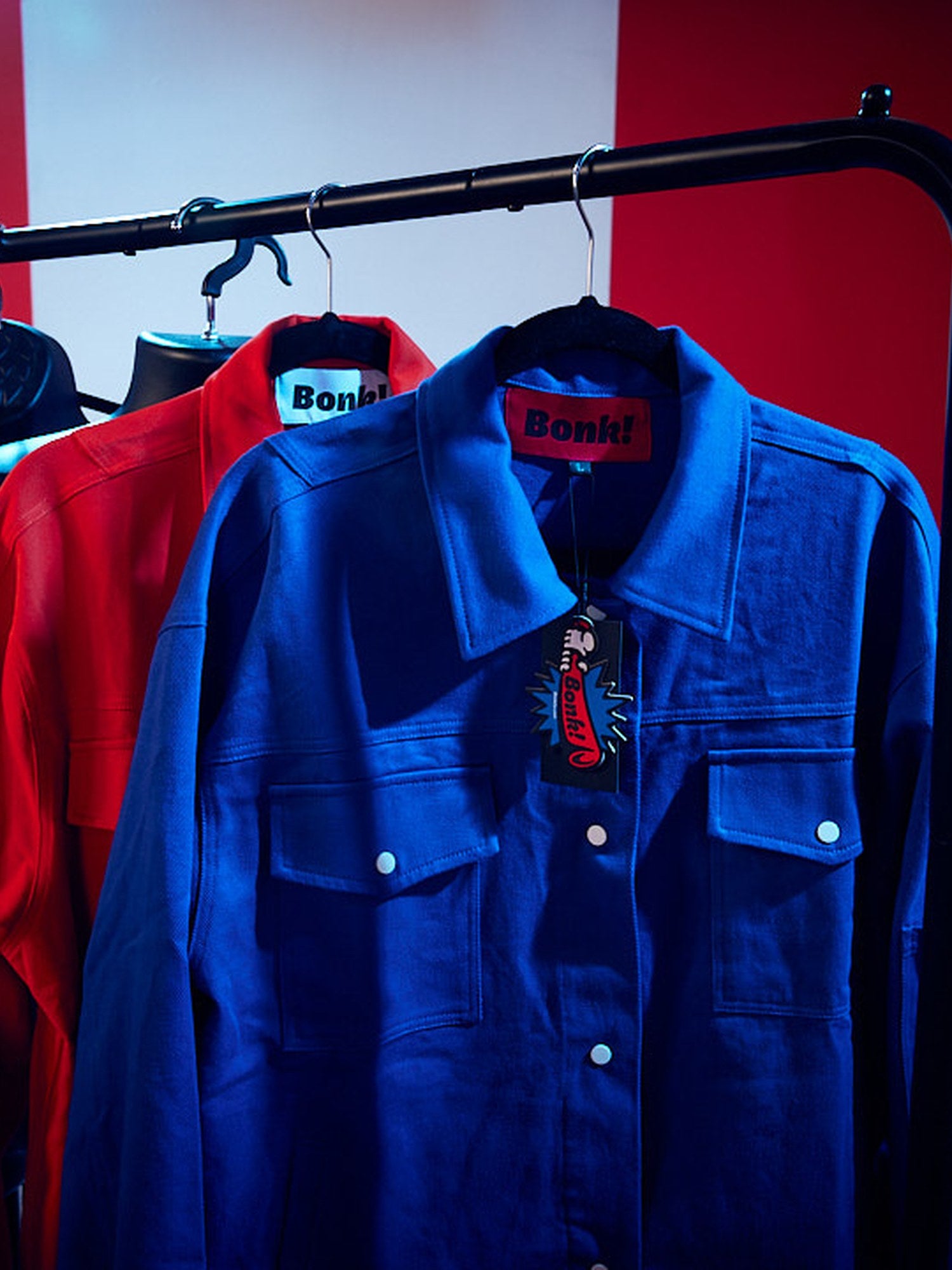 Blue and red Bonk Supply jackets on a clothing rail