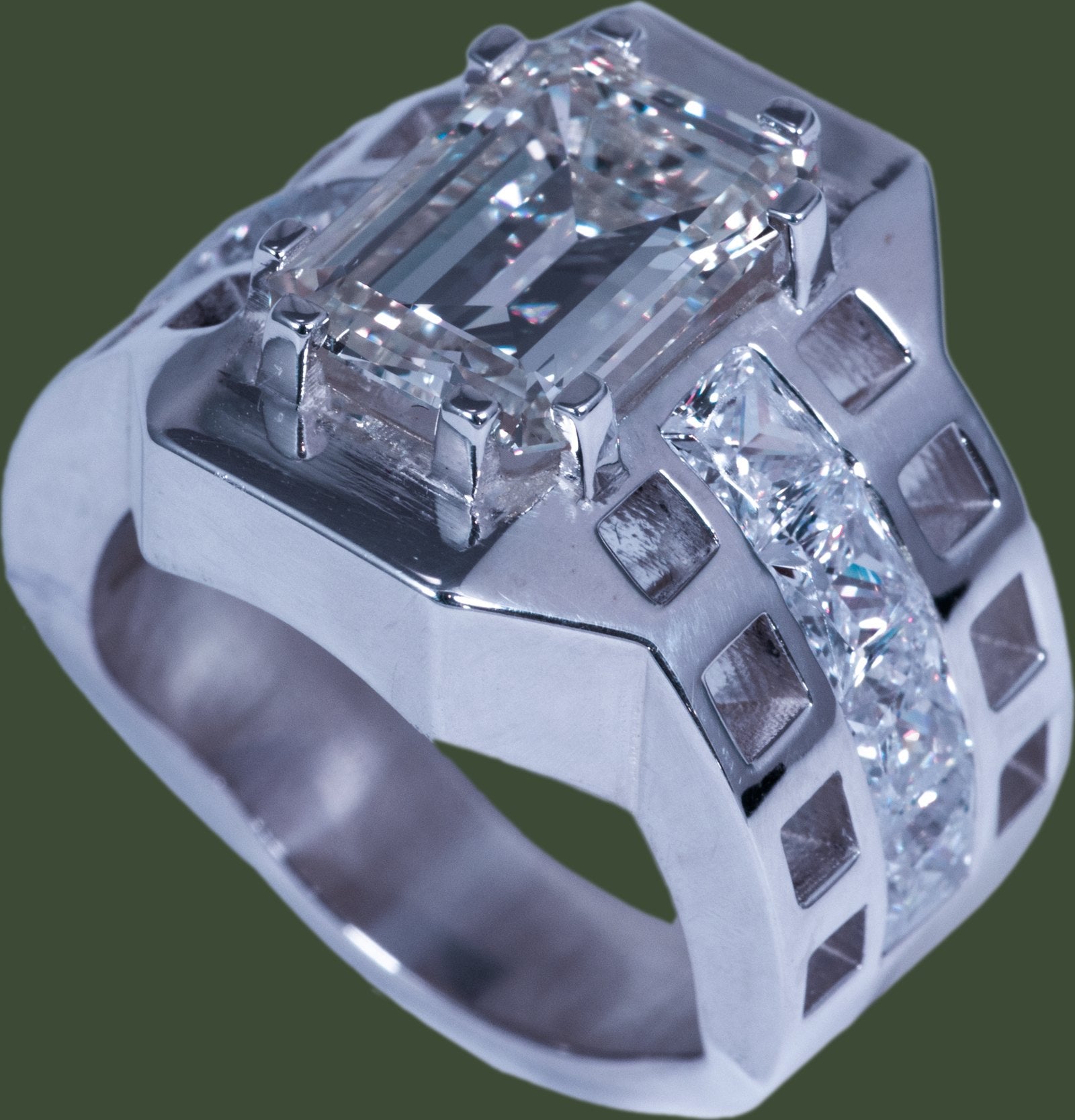 The photograph of the finished silver ring with an emerald-cut diamond and a channel of square stones.